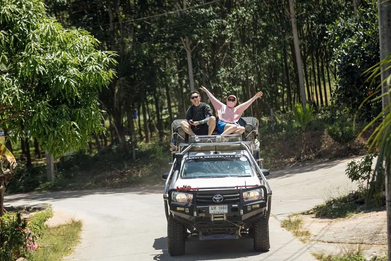 Guests waving from the roof of the 4x4 safari truck on a forest road
