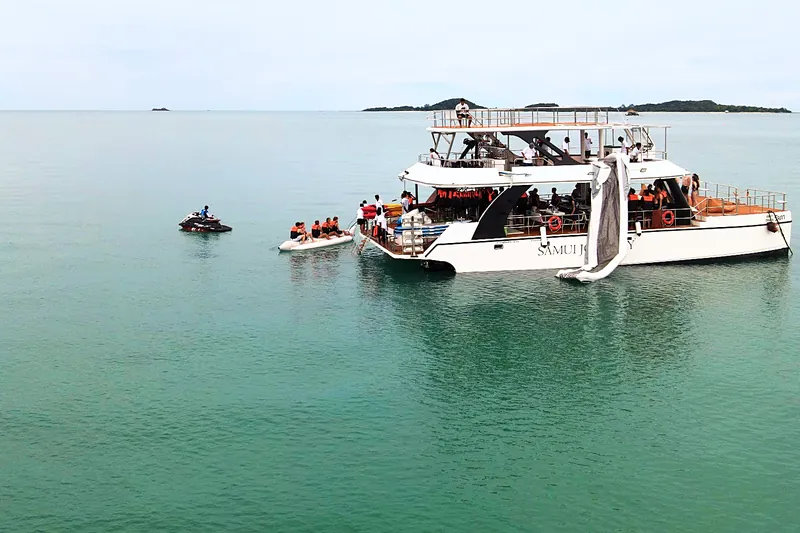 Guests in life jackets on the banana boat beside the catamaran, one of the Koh Samui water activities included on board
