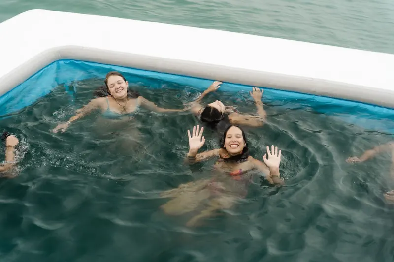 Guests waving from the floating sea pool beside the catamaran
